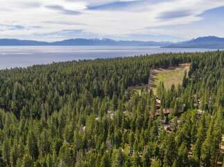 Nestled amidst a dense pine forest, this property offers a serene retreat with stunning views of a vast lake and distant snow-capped mountains.