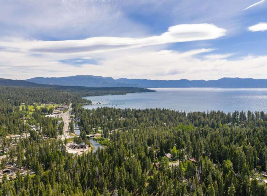 Discover this stunning aerial view of a lakeside community nestled amidst a dense forest of pine trees.