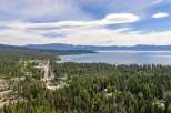 Discover this stunning aerial view of a lakeside community nestled amidst a dense forest of pine trees.