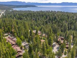 Nestled amidst a dense forest, this property offers a serene retreat with stunning views of a vast lake and distant mountains.