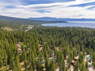 Nestled amidst a dense forest of pine trees, this property offers a serene retreat with stunning views of a distant lake and mountains.