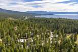 Nestled amidst a dense forest of towering pine trees, this property offers a serene escape with stunning views of a vast, blue lake and distant mountains.