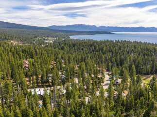 Nestled amidst a dense forest of towering pine trees, this property offers a serene escape with stunning views of a vast, blue lake and distant mountains.