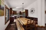 This spacious kitchen and dining area features rich, dark wood cabinetry complemented by a large, rustic butcher block dining table and benches.