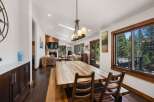Experience rustic charm and modern comfort in this spacious dining and living area, featuring a large wooden dining table perfect for gatherings.