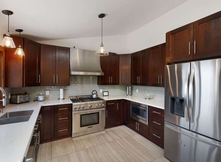 Experience luxury in this stunning kitchen featuring rich, dark wood cabinetry and sleek stainless steel appliances.
