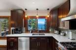 Experience breathtaking lake views from this stunning kitchen, featuring rich dark wood cabinetry and a spacious double sink.