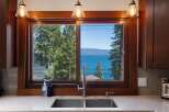 Experience breathtaking lake views from this stunning kitchen, featuring a large window overlooking the water and lush green trees.