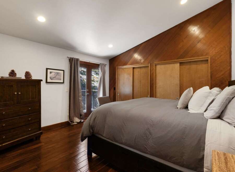 Experience rustic charm in this inviting bedroom, featuring a dark wood dresser adorned with pinecones and a framed piece of art.