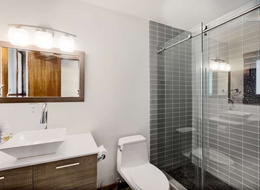 This modern bathroom features a sleek vanity with a vessel sink and a stylish wood-grain cabinet.