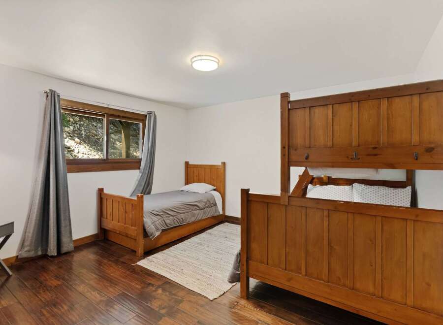 This cozy bedroom features a charming wooden bunk bed and a twin bed, perfect for accommodating family or guests.