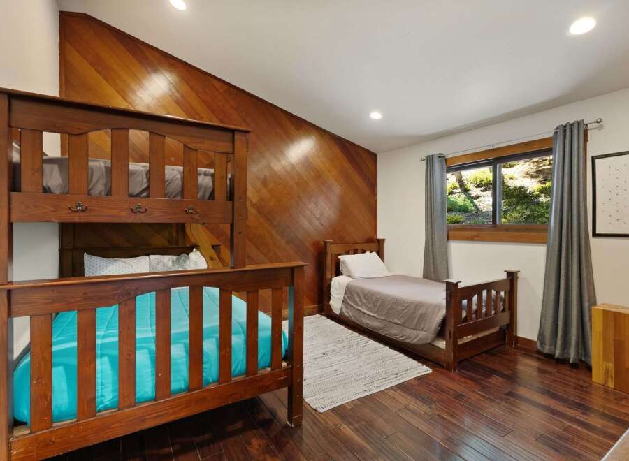 This charming bedroom features a sturdy wooden bunk bed and a separate twin bed, perfect for accommodating family or guests.