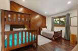 This charming bedroom features a sturdy wooden bunk bed and a separate twin bed, perfect for accommodating family or guests.
