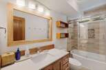 This modern bathroom features a sleek vanity with a white countertop and wooden cabinets, complemented by a large wooden-framed mirror.