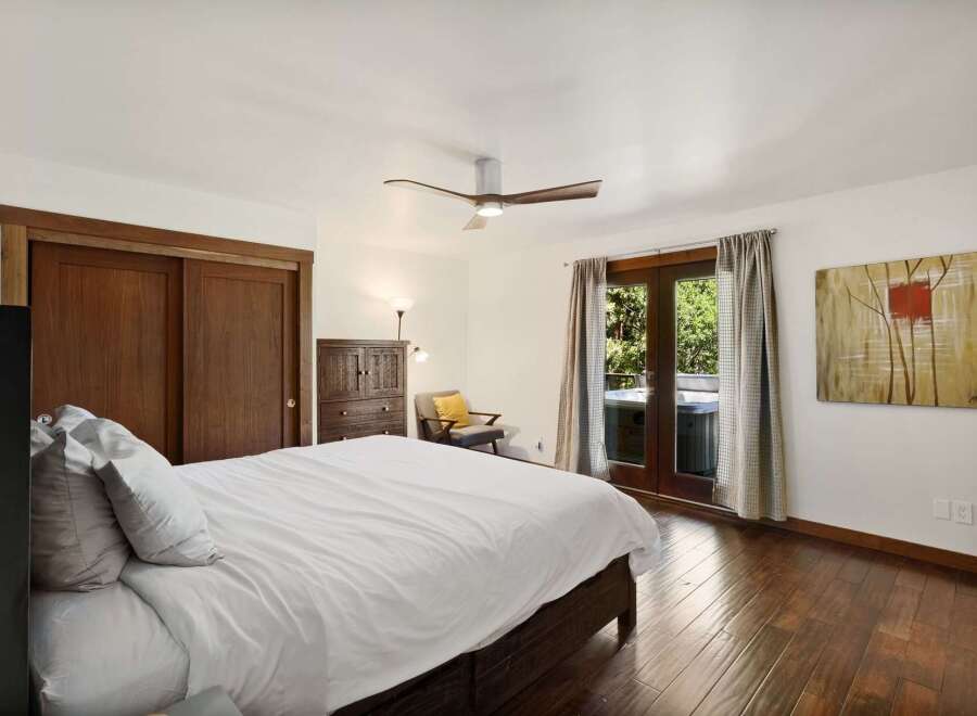 Experience ultimate relaxation in this serene bedroom featuring a comfortable king-size bed and direct access to an outdoor oasis.
