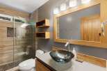 Experience modern luxury in this stunning bathroom featuring a spacious walk-in shower with natural stone accents and elegant wood-grain tile.