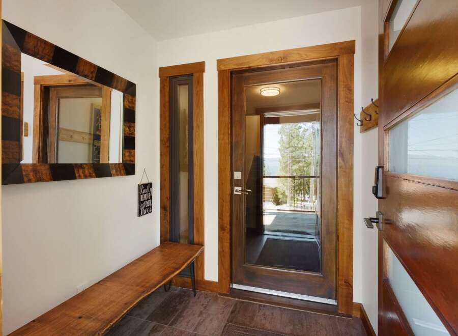 Step into a warm and inviting entryway featuring a stunning live-edge wooden bench and a unique striped mirror.