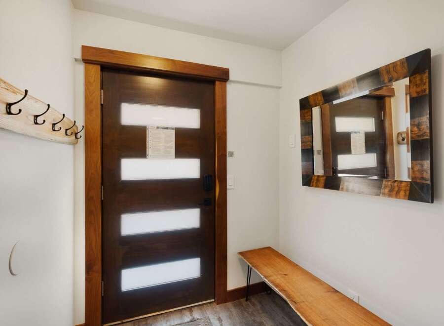 Step into a welcoming entryway featuring a stylish dark wood door with frosted glass panels, perfect for modern living.