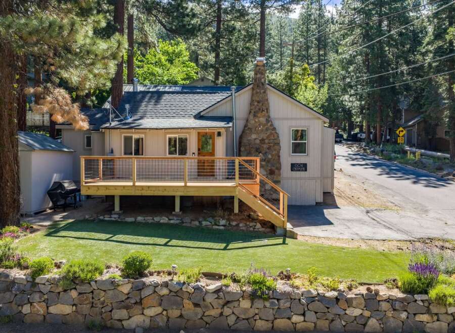 Charming single-family home nestled among tall pine trees, featuring a spacious wooden deck perfect for outdoor relaxation and entertaining.