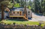Charming single-family home nestled among tall pine trees, featuring a spacious wooden deck perfect for outdoor relaxation and entertaining.