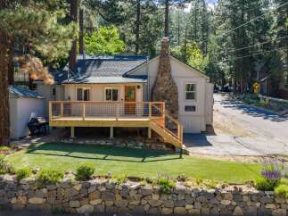 Charming single-family home nestled among tall pine trees, featuring a spacious wooden deck perfect for outdoor relaxation and entertaining.