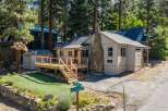 Charming cabin nestled among tall pine trees, featuring a spacious wooden deck perfect for outdoor relaxation and entertaining.