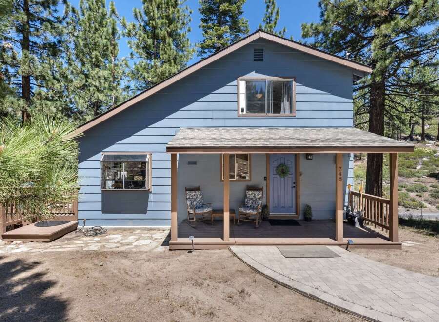 Charming blue home nestled among tall pine trees, offering a serene mountain retreat.