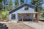 Charming blue home nestled among tall pine trees, offering a serene mountain retreat.