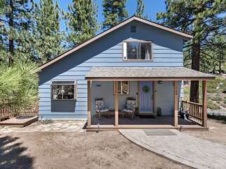 Charming blue home nestled among tall pine trees, offering a serene mountain retreat.
