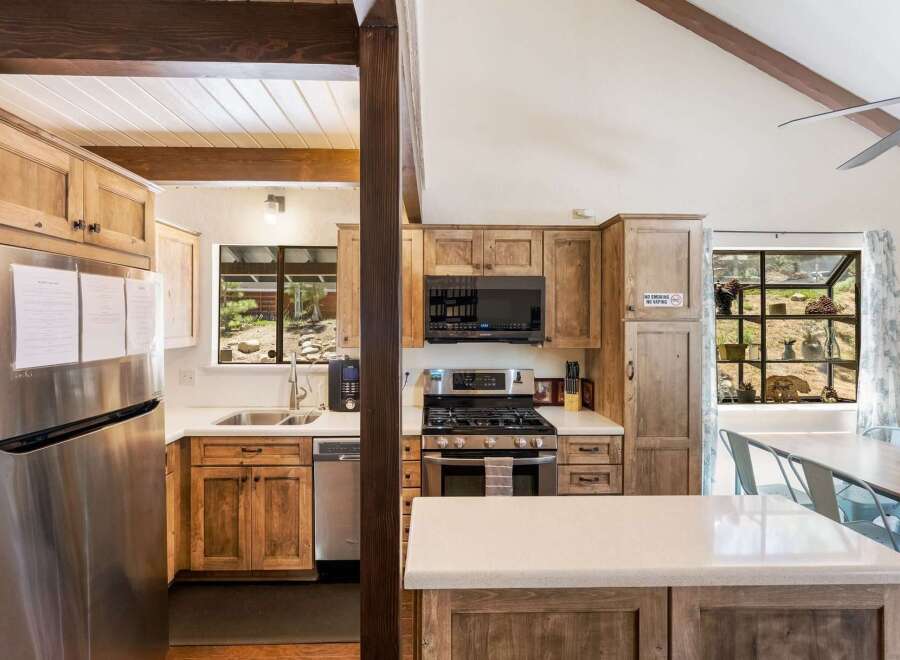 Experience rustic charm in this spacious kitchen featuring warm wooden cabinetry and a large stainless steel refrigerator.