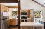 Experience rustic charm in this spacious kitchen featuring warm wooden cabinetry and a large stainless steel refrigerator.