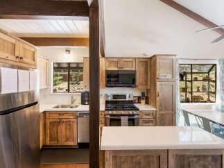 Experience rustic charm in this spacious kitchen featuring warm wooden cabinetry and a large stainless steel refrigerator.