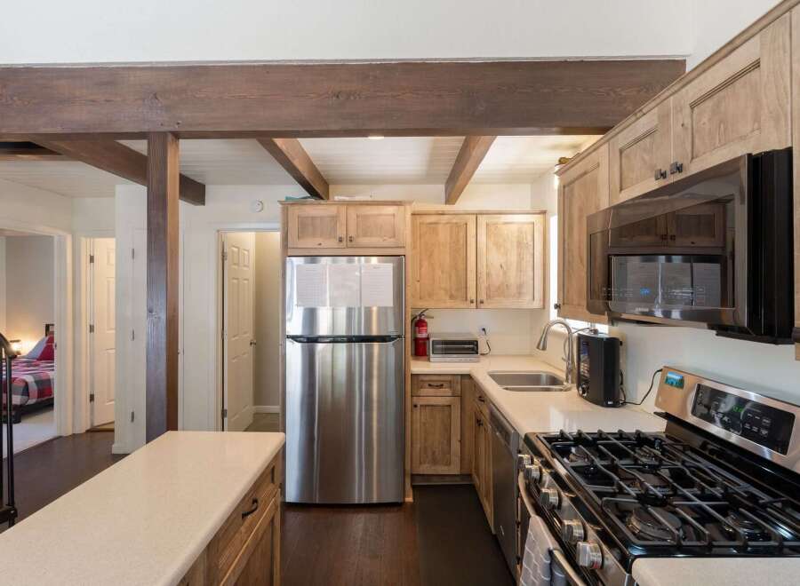 Discover this charming kitchen featuring rustic wooden cabinetry and a sleek stainless steel refrigerator.