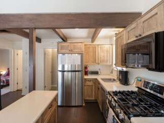 Discover this charming kitchen featuring rustic wooden cabinetry and a sleek stainless steel refrigerator.