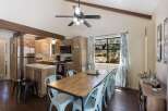 Experience rustic charm in this inviting kitchen and dining area, featuring vaulted ceilings with exposed beams and a ceiling fan for optimal comfort.