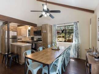 Experience rustic charm in this inviting kitchen and dining area, featuring vaulted ceilings with exposed beams and a ceiling fan for optimal comfort.
