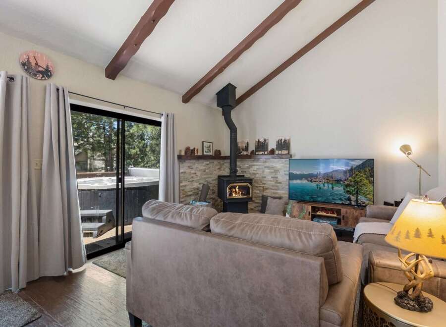 Experience ultimate relaxation in this cozy living room featuring a stone-accented fireplace and a large flat-screen TV.