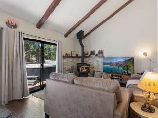 Experience ultimate relaxation in this cozy living room featuring a stone-accented fireplace and a large flat-screen TV.