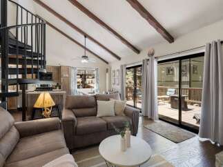 Experience cozy living in this charming cabin featuring a vaulted ceiling with exposed wooden beams and a striking spiral staircase.