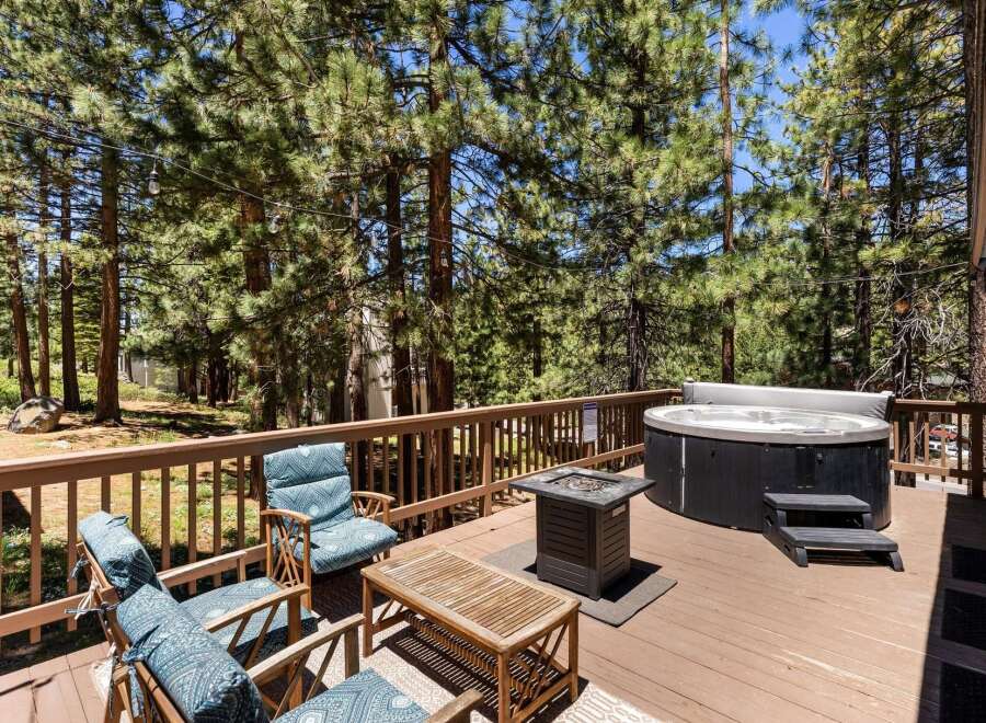 Relax and unwind on this spacious wooden deck, surrounded by the serene beauty of tall pine trees.