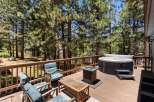 Relax and unwind on this spacious wooden deck, surrounded by the serene beauty of tall pine trees.
