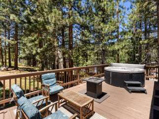Relax and unwind on this spacious wooden deck, surrounded by the serene beauty of tall pine trees.