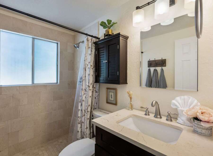 This beautifully updated bathroom features a spacious walk-in shower with elegant tile work and a frosted window for privacy.