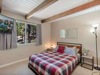 Experience cozy mountain living in this charming bedroom featuring a comfortable bed with a classic plaid comforter.
