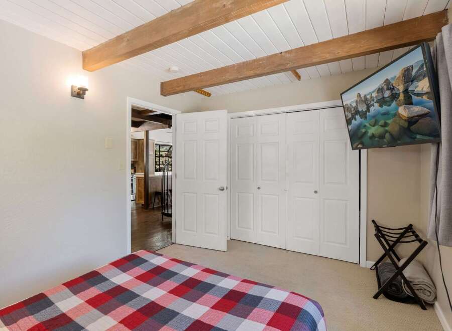 Experience cozy comfort in this charming bedroom featuring a striking red, white, and gray plaid comforter on the bed.