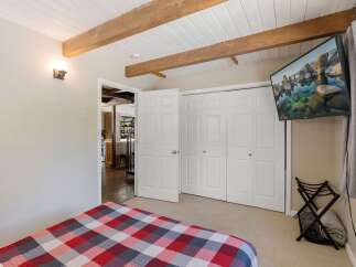 Experience cozy comfort in this charming bedroom featuring a striking red, white, and gray plaid comforter on the bed.