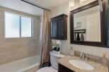 This bathroom features a bathtub with a tiled wall and a frosted window, complemented by a beige shower curtain.