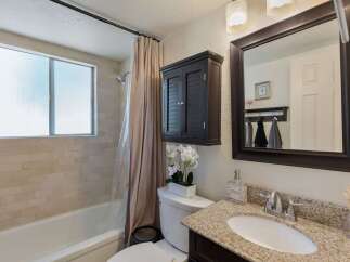This bathroom features a bathtub with a tiled wall and a frosted window, complemented by a beige shower curtain.