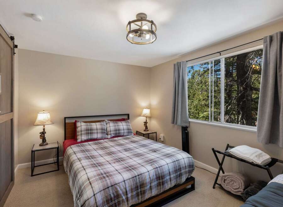 Experience cozy comfort in this charming bedroom featuring a plaid comforter and matching pillows, perfect for a restful night's sleep.