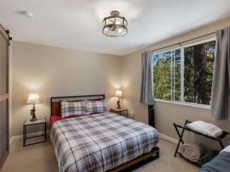 Experience cozy comfort in this charming bedroom featuring a plaid comforter and matching pillows, perfect for a restful night's sleep.
